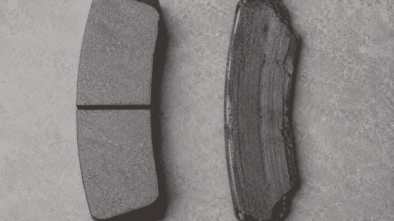 A car odometer showing mileage reading alongside new and worn brake pads placed side by side for comparison