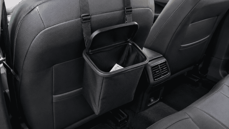 A small black car trash bin hanging from the back of a front seat headrest, keeping the car interior tidy