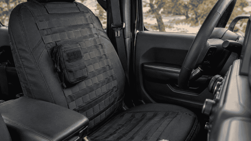 Tactical MOLLE system seat cover installed on a Jeep Wrangler front seat with webbing panels visible for gear attachment