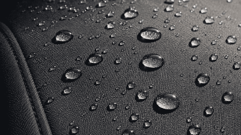 Water droplets beading up on the surface of a vinyl car seat cover demonstrating its waterproof properties