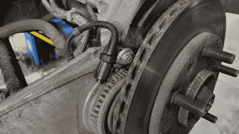 A wheel speed sensor visible at the brake assembly near the wheel hub, showing the small sensor that monitors wheel rotation speed for the traction control and ABS systems