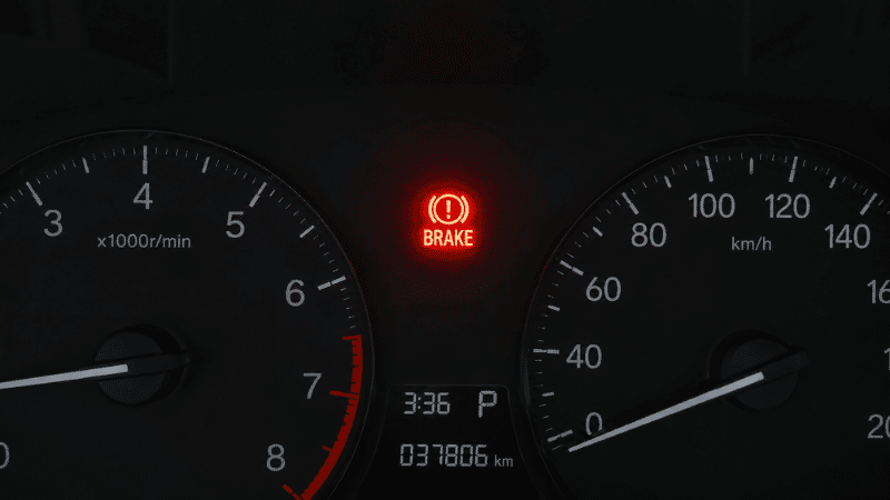 A car dashboard showing a red brake warning light illuminated with the word BRAKE or exclamation mark in circle symbol glowing against the dark instrument cluster