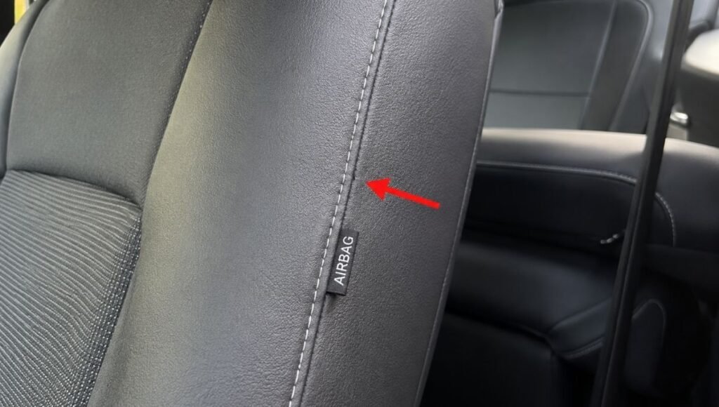Close-up of a car seat cover outer bolster area showing the intentional breakaway seam stitching designed to split during side airbag deployment for SRS compatibility