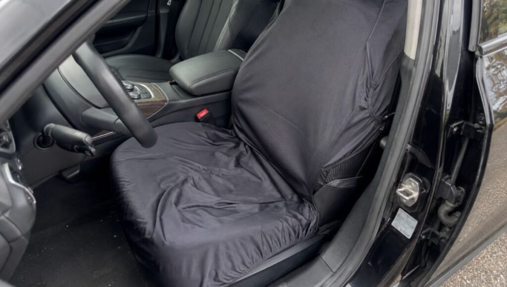 A universal car seat cover showing visible bunching excess fabric and poor fit on a car seat with the cover sliding and not conforming to the seat contours