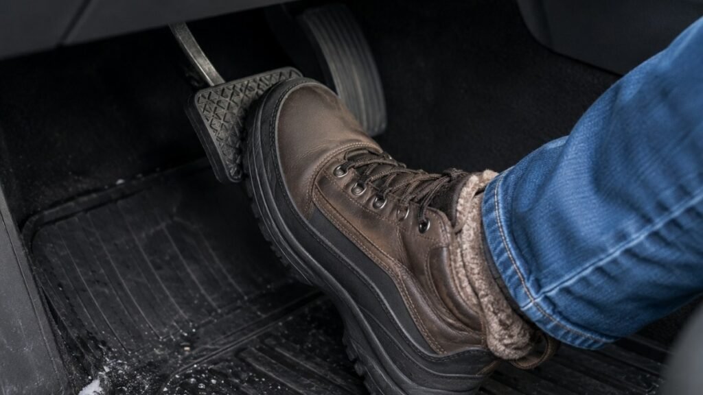 Close-up of a driver's foot pressing firmly on the brake pedal during ABS activation on a snowy road showing the correct technique of holding the pedal steady during the pulsing sensation
